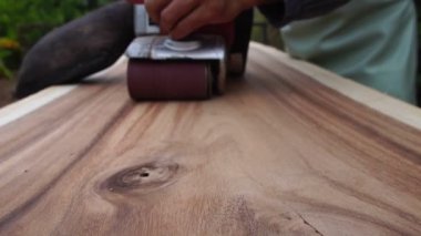Male carpenter is using electric woodworking tool to work outdoors