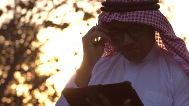 日没時にタブレット技術を使用して民族衣装を身に着けているアラブビジネスマン — ストック動画
