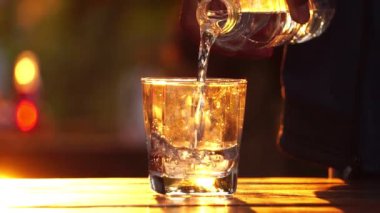 close-up footage of man pouring glass of water on sunset background