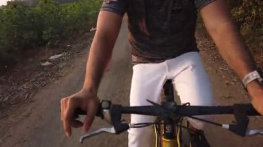Kırsal yolda bisiklet süren bir adamın kırpılmış görüntüleri.