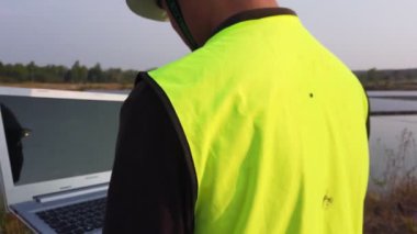 Balıkçılık sırasında göl kenarında dizüstü bilgisayarlı bir adamın kırpılmış görüntüleri.