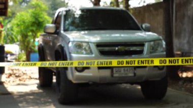 close-up footage of do not enter ribbon in front of vehicle at place of crime while policeman walking around