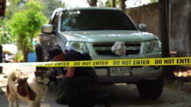 close-up footage of do not enter ribbon in front of vehicle at place of crime while policeman walking around with dog