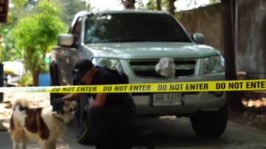 close-up footage of do not enter ribbon in front of vehicle at place of crime while policeman walking around with dog