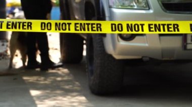 close-up footage of do not enter ribbon in front of vehicle at place of crime while policeman walking around