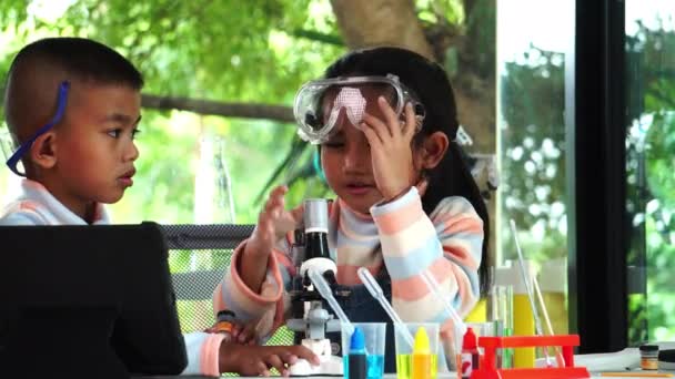 アジアの学校の子供たちは 学校の実験室で顕微鏡を使って化学を学んでいる — ストック動画