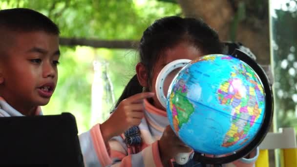 Ασιατικά Παιδιά Που Επιθεωρούν Ένα Μοντέλο Της Γης Μεγεθυντικό Φακό — Αρχείο Βίντεο