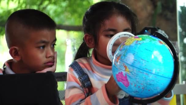 Asiatische Kinder Begutachten Ein Modell Der Erde Mit Der Lupe — Stockvideo