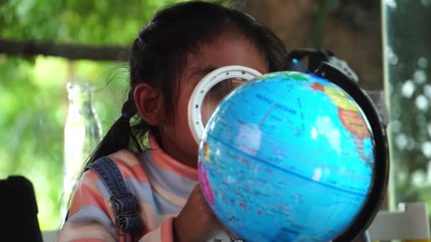 壮大なガラスで地球のモデルを検査するアジアの少女 — ストック動画