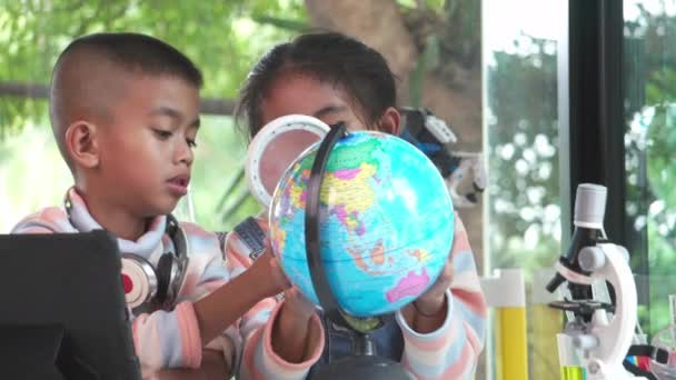 Azjatyckie Dzieci Sprawdzające Model Ziemi Szkłem Powiększającym — Wideo stockowe