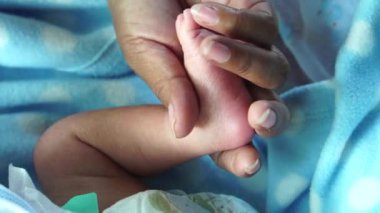 Anne yeni doğan bebeğinin bacağını tutuyor.