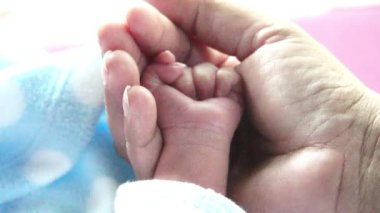 Anne yeni doğmuş bebeğinin elini tutuyor. 