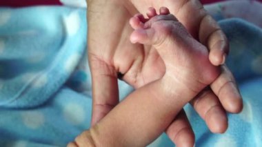 Anne yeni doğan bebeğinin bacağını tutuyor.