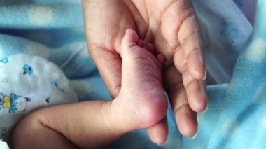 Anne yeni doğan bebeğinin bacağını tutuyor.