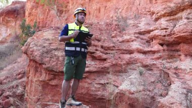 Jeolog dışarıdan mineralleri inceliyor ve dijital tablet kullanıyor.