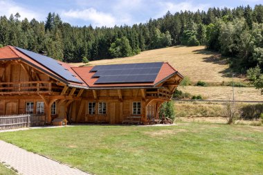 Dağın tepesinde güneş panelleri olan modern ahşap dağ evi.