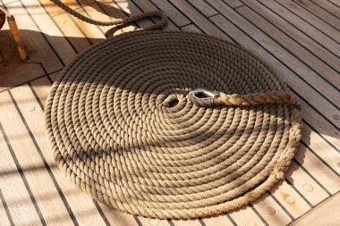 Yelkenli geminin ahşap güvertesinde yuvarlanmış ip.