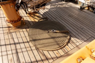 Yelkenli geminin ahşap güvertesinde yuvarlanmış ip.