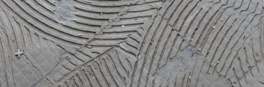 Panoramic image. Background of old grey tile adhesive on the floor. Abstract pattern of notched trowel clipart
