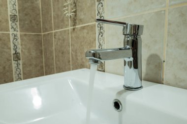 Lavaboya doğru akan temiz suyu olan bir musluk.