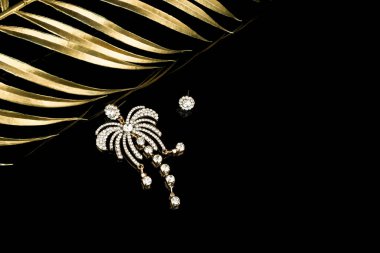 Siyah arkaplanda elmaslarla izole edilmiş altın küpeler.