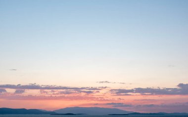 Gün batımında kırmızı, sarı ve mavi gökyüzünün altında ufkun hemen üstünde bulutlar.
