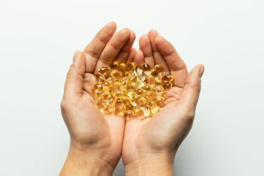 Ellerinde D3 vitamini kapsülleri var. Metin için beyaz arkaplan.