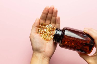 Paketten D3 vitamini kapsülleri döküldü. Sağlık ve dokunulmazlık için. Bir kadın eli..