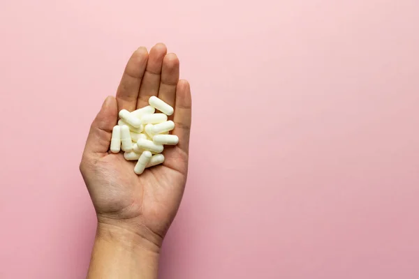 Elinde pembe arka planda çinko tabletler var..