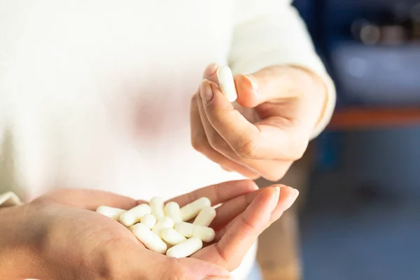 Woman holding white capsules in her hands, health care, drug dosage, supplementation