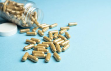 Capsules of plant origin of a dietary supplement on a blue background, body support, health care, medical product