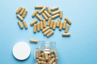 Capsules of plant origin of a dietary supplement on a blue background, body support, health care, medical product