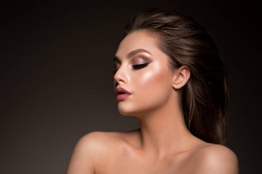 Glamour portrait of a beautiful woman model with fresh daily makeup and a romantic hairstyle. Fashion shiny highlighter on skin and dark eyebrows. High-quality photo