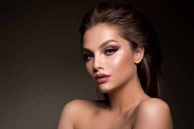 Glamour portrait of a beautiful woman model with fresh daily makeup and a romantic hairstyle. Fashion shiny highlighter on skin and dark eyebrows. High-quality photo