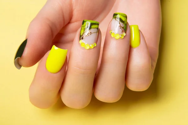 Female hands with black and yellow nail design. Yellow nail polish manicured hands. Female hands on yellow background. High quality photo