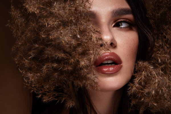 Красивая женщина с ярким макияжем. Красивая девушка с цветами. Потрясающая брюнетка с большим букетом. Крупный план лица молодой красивой женщины со здоровой чистой кожей. Высокое качество фото