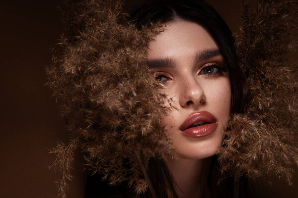 Красивая женщина с ярким макияжем. Красивая девушка с цветами. Потрясающая брюнетка с большим букетом. Крупный план лица молодой красивой женщины со здоровой чистой кожей. Высокое качество фото