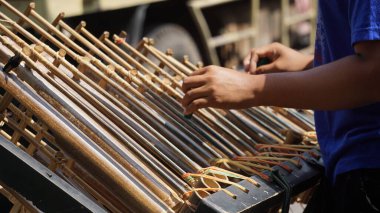 Bir adam angklung oynuyor. Bu, Sundan halkının geliştirdiği çok tonlu bir müzik aleti. Angklung bambudan yapılır.