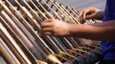 Bir adam angklung oynuyor. Bu, Sundan halkının geliştirdiği çok tonlu bir müzik aleti. Angklung bambudan yapılır.