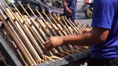 Bir adam angklung oynuyor. Bu, Sundan halkının geliştirdiği çok tonlu bir müzik aleti. Angklung bambudan yapılır.