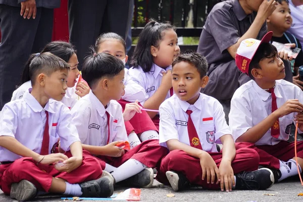 stock image Indonesian elementary school students with their friends holding red and white flags