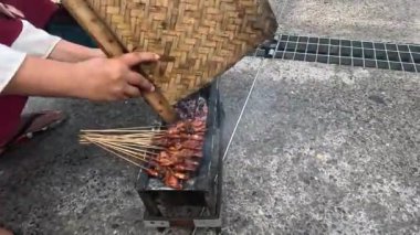 İnsanlar yemek pişirir. Sate, fıstık sosuyla servis edilen geleneksel Endonezya yemeklerinden biridir.