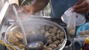 Bakso satıcısı (köfte satıcısı) bir tezgah arabasında müşterilere servis yapar. Bakso, Endonezya sokak yemeklerinden biridir.