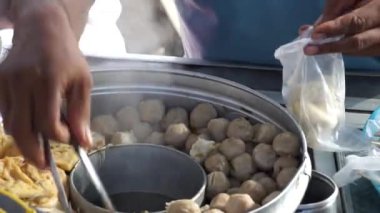 Bakso satıcısı (köfte satıcısı) bir tezgah arabasında müşterilere servis yapar. Bakso, Endonezya sokak yemeklerinden biridir.