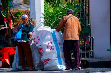 Eski püskü giysiler içinde yaşlı insanlar satmak için plastik şişe arıyorlar.