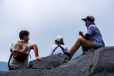 Kelud Dağı manzaralı büyük bir kayanın üzerinde yabancı turistler