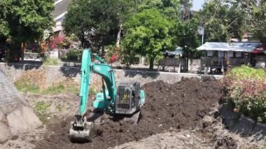 Kazı makinisti, suyun akmasını sağlamak için nehirde toprak kazıyor.