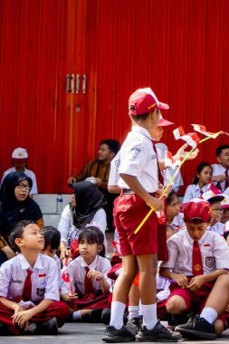 Endonezyalı üniformalı ilkokul öğrencileri Endonezya bayrağını sokaklara mutlulukla taşıdı
