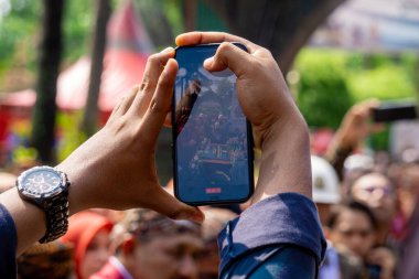 İki el bir etkinlik kaydetmek için telefonu tutuyor.