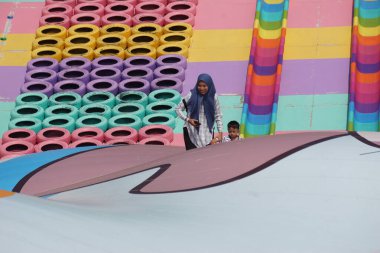 People play rainbow  slide at Dusun Semilir during holidays. Dusun Semilir is a famous tourist attraction in Semarang clipart